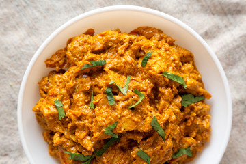 Homemade Chicken Tikka Masala in a white bowl on cloth, top view. Flat lay, overhead, from above.