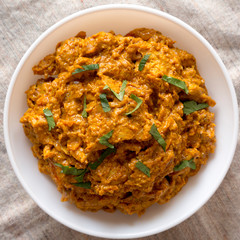 Homemade Chicken Tikka Masala in a white bowl on cloth, top view. Flat lay, overhead, from above. Close-up.