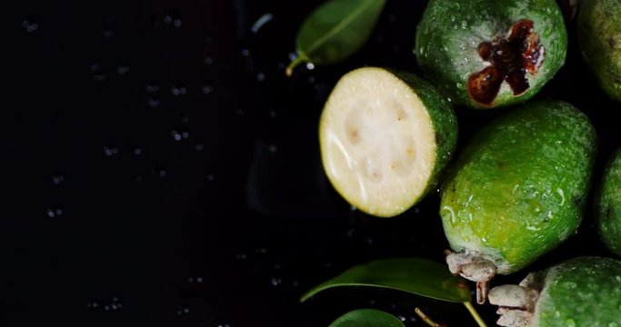 Fresh feijoas with leaves falling drops of water.