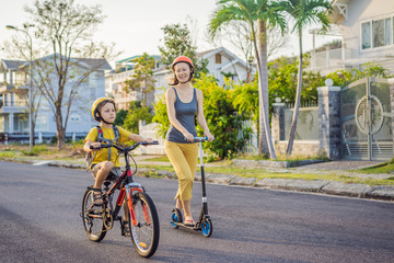 Active school kid boy and his mom in safety helmet riding a bike with backpack on sunny day. Happy child biking on way to school. Safe way for kids outdoors to school