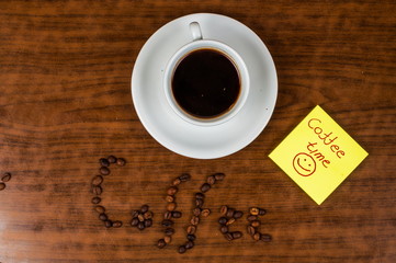 White coffee cup and coffee beans on a wooden table.Coffee time