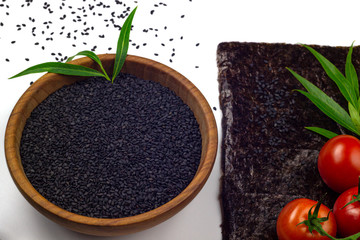 Black sesame in wooden bowl, nori sheets and potatoes isolated on white background