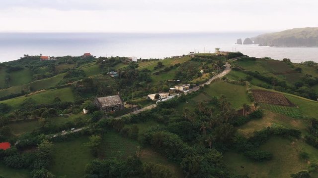Aerial shot of an old church and the houses around it on a hilltop within a small island