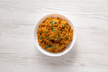 Homemade Chicken Tikka Masala in a white bowl on a white wooden surface, top view. Flat lay, overhead, from above.
