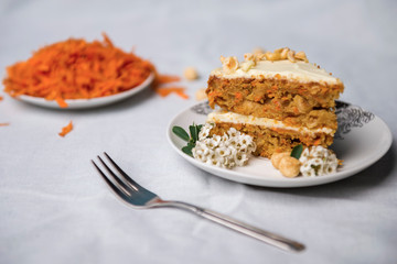 Piece of carrot decorated with white flowers and grated carrots on the background