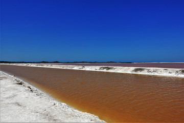 Amazing color contrast in nature. Mexico. Bright blue sky, pink salt lake, orange river from industrially processed water and white sand on the shore. Incredible colors.