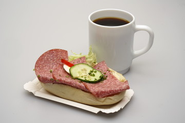 Ein Halbes Belegtes Brötchen mit Salami, Tasse Kaffee