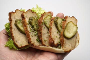 Ein Halbes Belegtes Brötchen mit Bulette in Hand