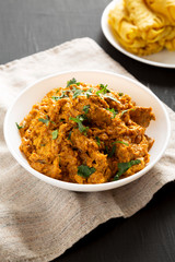 Homemade Chicken Tikka Masala in a white bowl on a black surface, side view.