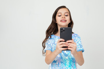 Fototapeta premium young girl in a blue t-shirt makes a photo on a smartphone on a white studio background