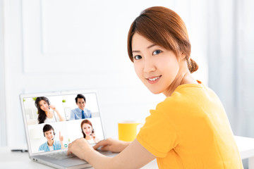 young woman working at home and using laptop computer with video conference