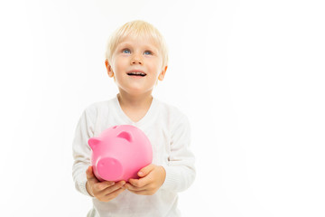 Little blonde caucasian boy with pink pig moneybox isolated on white background