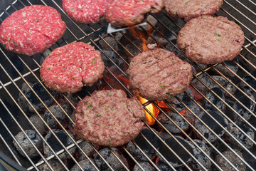 Close-up view of meatball grilling on barbecue. Grilled burger on barbecue grill with smoke and black background. .