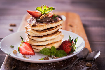 Pancakes  with chocolate sauce and fresh  strawberries on brawn wooden background. Delicious sweet dessert.