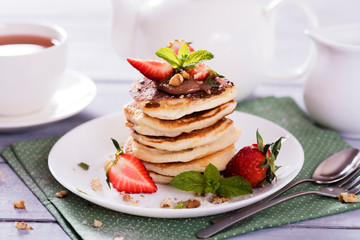 Pancakes  with chocolate sauce and fresh  strawberries on white wooden background. Delicious sweet dessert.