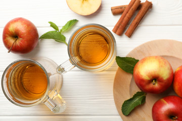 Composition with cider, cinnamon and apples on white wooden background