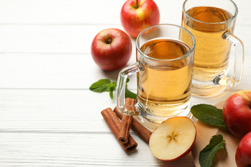 Composition with cider, cinnamon and apples on white wooden background