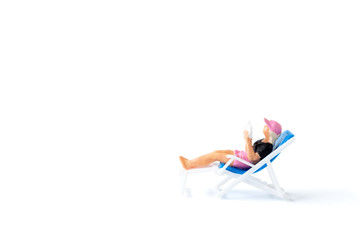 Miniature people sunbathing on deck chairs on white background , Summer time concept