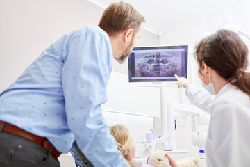 Zahnarzt und ZFA schauen auf Röntgenbild
