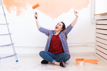 Happy smiling woman painting interior wall of new house. Redecoration, renovation, apartment repair and refreshment concept.