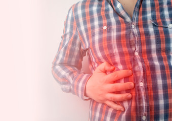 A man grabs his right side under the ribs. Pain in the liver. Pain syndrome in liver disease.