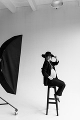 Beautiful pregnant woman in underwear, a black suit and hat in the studio. Black-white photo of a pregnant woman in the studio.