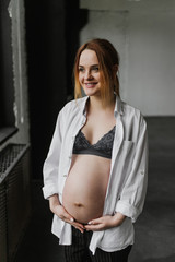 Beautiful pregnant woman in underwear and a shirt in the studio.