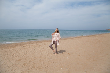 Beautiful blonde woman walks on the sea beach alone