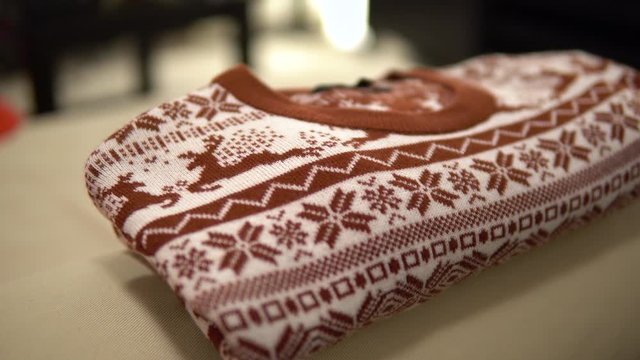 A Christmas sweater folded on a piece of furniture in an apartment - closeup
