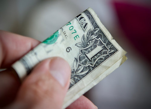 Mans hand offering a dollar bill