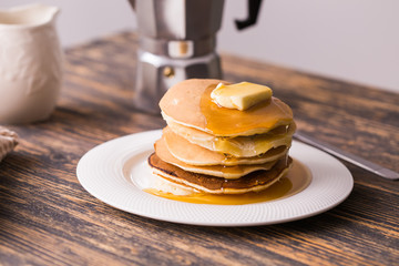 Small pancakes with maple syrup and butter on wooden table. Breakfast concept.