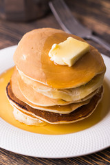 Small pancakes with maple syrup and butter on wooden table. Breakfast concept.