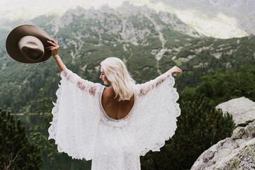 Beautiful bride in a boho style dress and hat in the mountains. Wedding photo shoot in the mountains. © Oksana