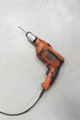 Orange electric drill over gray floor