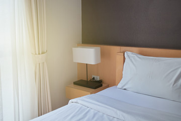 Hotel apartment or condominium bedroom with lamp above side table. Close up and selective focus.