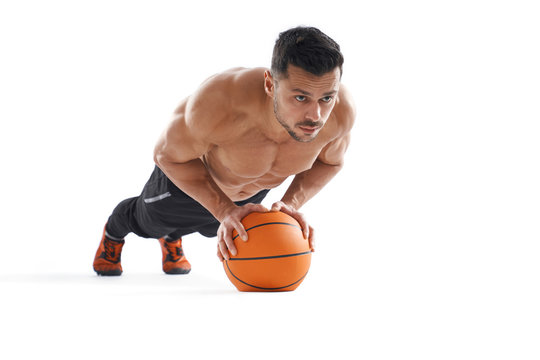 Shirtless bodubuilder doing push ups using basketball.