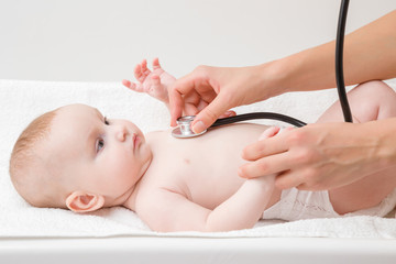 Young woman hand holding stethoscope and listening baby girl heartbeat. Close up. Regular examining...