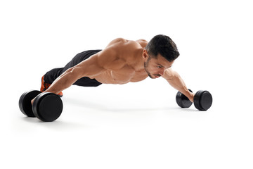 Bodybuilder doing wide push ups using dumbbells.