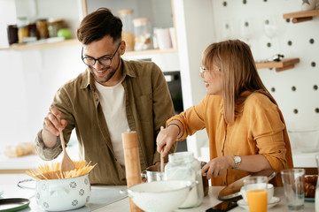 Young couple cooking together at home. Loving couple having fun while cooking.