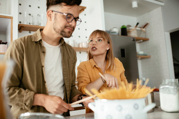 Young couple cooking together at home. Loving couple having fun while cooking.