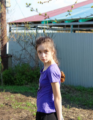 Portrait of a teenage girl in the spring on a plot of land. Help in the garden.