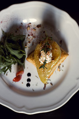 Baked pear with cheese and vegetables close-up in a restaurant.
