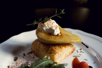 Baked pear with cheese and vegetables close-up in a restaurant.
