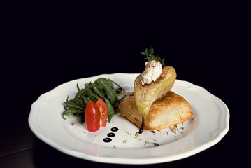 Baked pear with cheese and vegetables close-up in a restaurant.