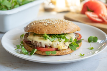 Homemade beef cheese burger with whole grain buns, tomatoes and microgreens close up, healthy food