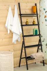 stairs with shelves for decorative bottles, towels hanging on the wooden wall and a wicker Laundry container in the Scandinavian-style bathroom
