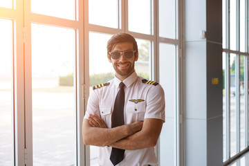 Emotional Confident Captain cross one's arm and Smiling at the airport. - obrazy, fototapety, plakaty