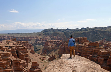 Man standing on a rock overseeing the magnificent landscape of Charyn Canyon, Kazakhstan