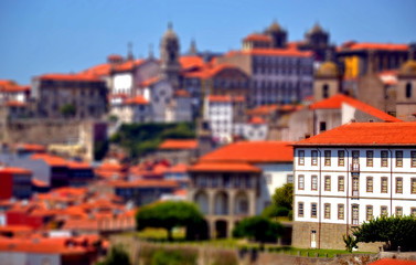 Fototapeta na wymiar Porto, Portugal - August 16, 2015: Cityscape of Porto in summer, with a good weather. This city is built along the river Douro, which goes to the sea. Focus on a building with tilt-shift effect.