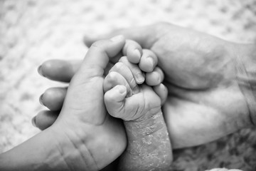 Newborn child hand. Closeup of baby hand into parents hands. Family, maternity and birth concept.